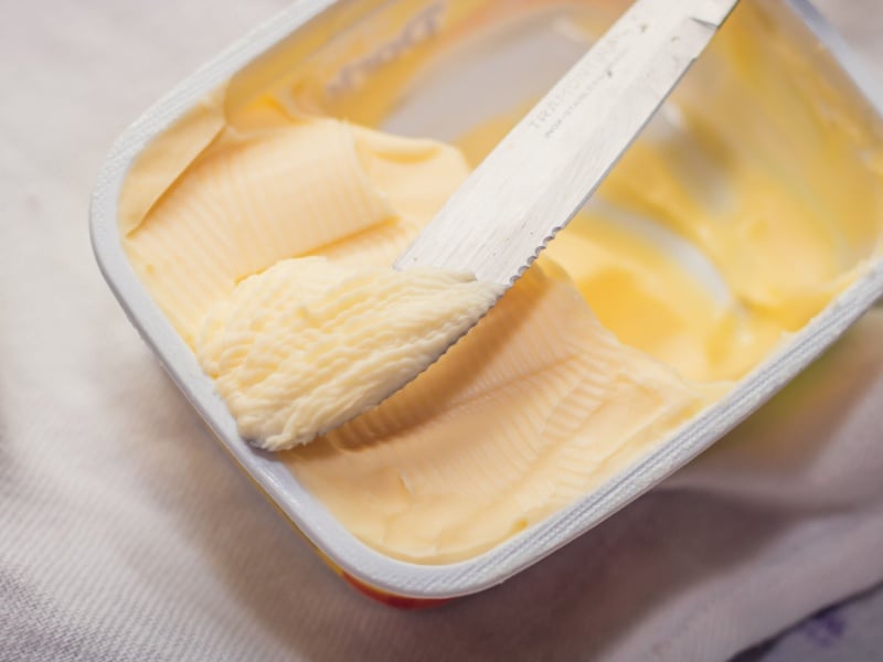 A knife in an open pot of margarine.