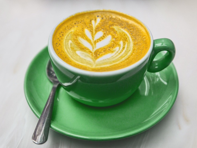 A cup of turmeric latte on a table.