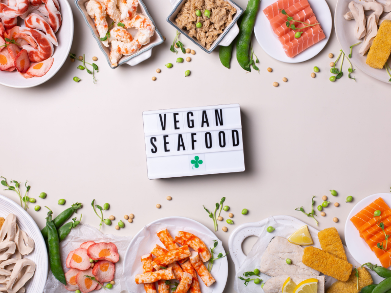 Top-down view of vegan fishes such as plant-based fish fingers, salmon, tuna and prawns with a sign saying vegan seafood..