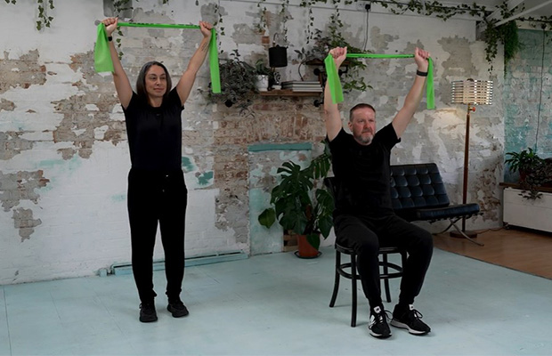 Hara Markos and Peter Richards doing a lat pull down with resistance bands.