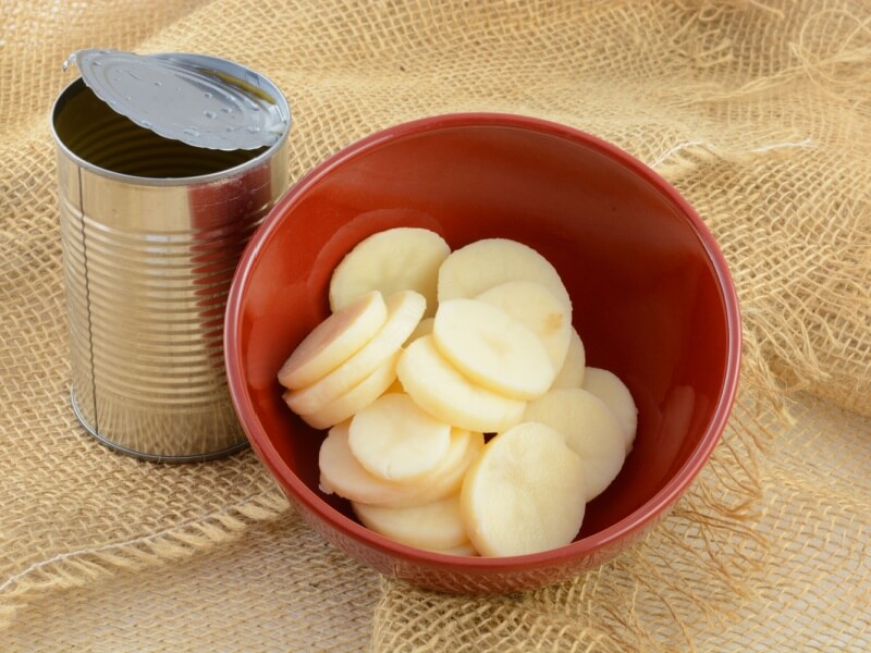 Canned potatoes in a bowl next to an empty tin.
