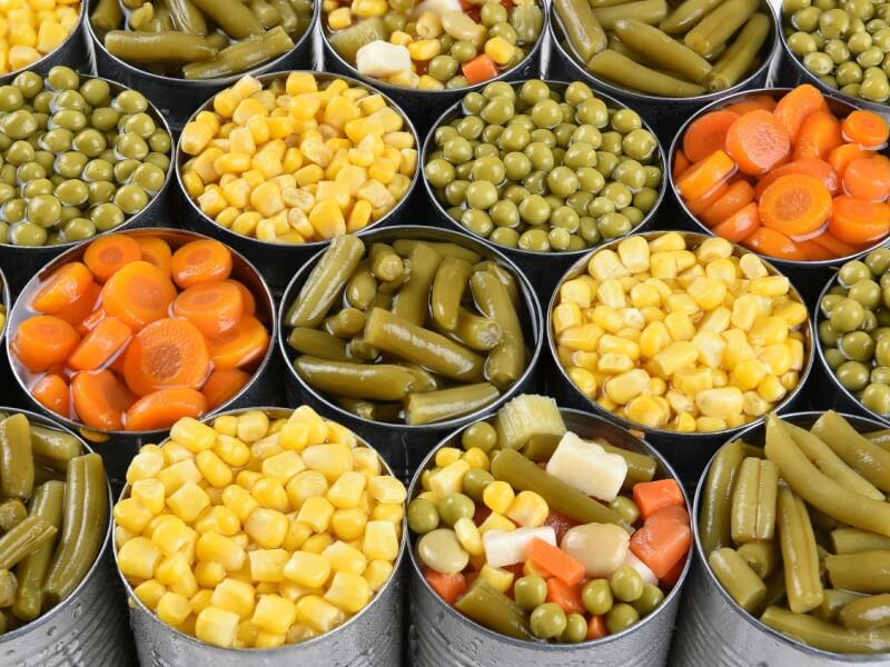 Lots of open tins containing different types of vegetables.