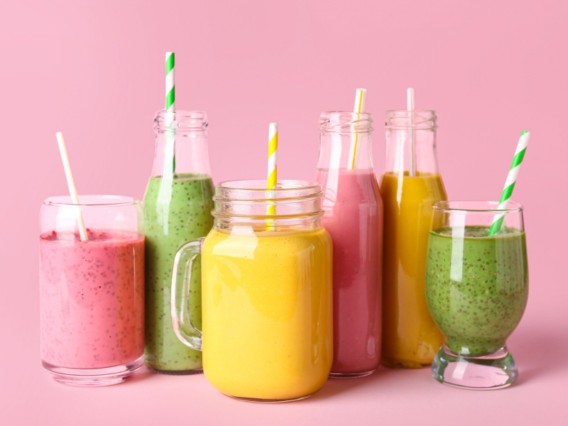 Six glasses of different coloured smoothies.