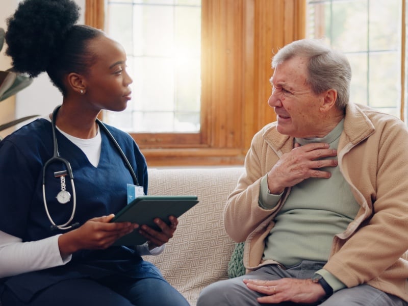 A healthcare professional speaking to a man with his hand on his chest.