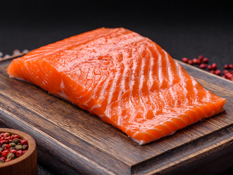 A fresh raw salmon steak next to some spices.