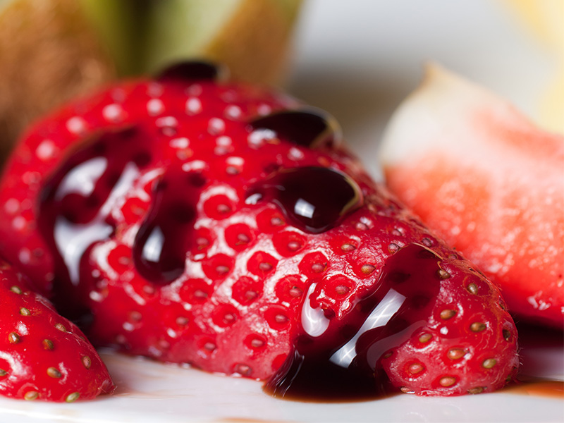 A strawberry with drops of balsamic vinegar on it.