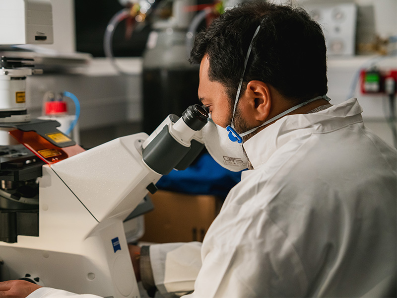 Dr Rikesh Rajani looking through a microscope as part of his research into vascular dementia.