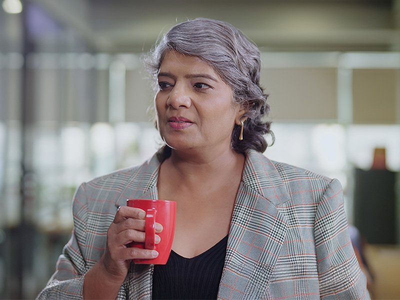 A woman in an office holding a mug,