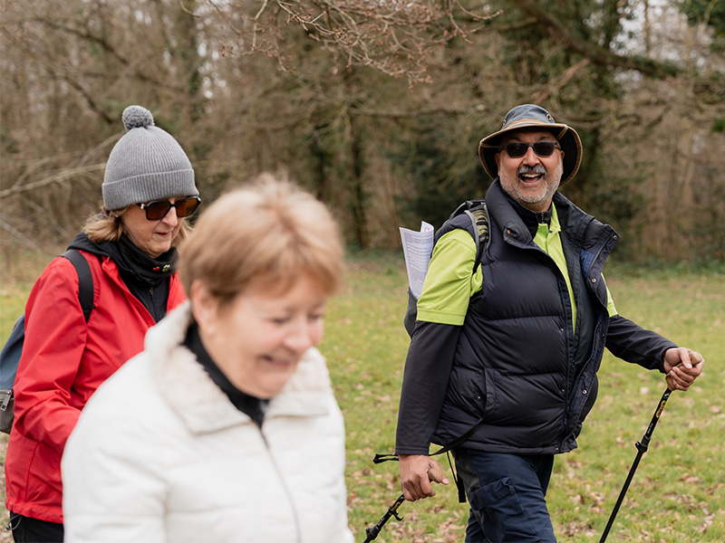 Denis Collen walking and chatting with a group of people in a park.