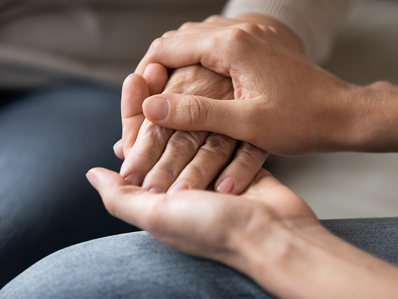 A close up of 2 women holding hands.