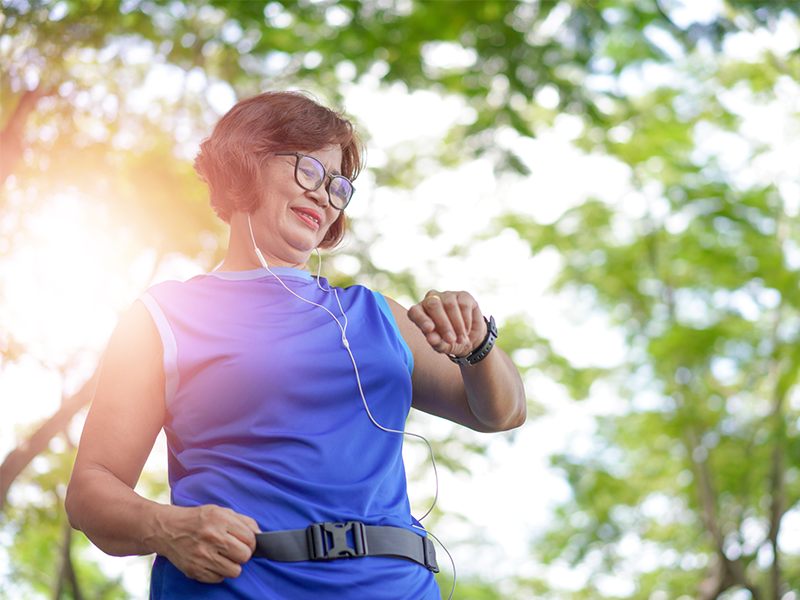 A woman exercising outdoors while checking her smart watch.