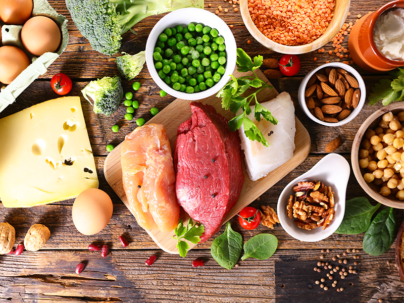 A table with foods high in protein, including meat, fish, cheese and nuts.