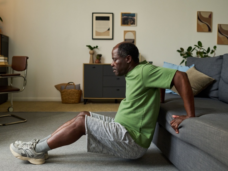 A man performing a tricep dip on a sofa.