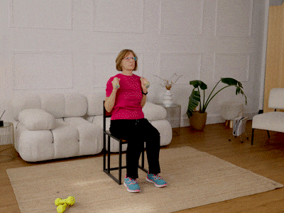 Nicola performing a seated shoulder press with weights.