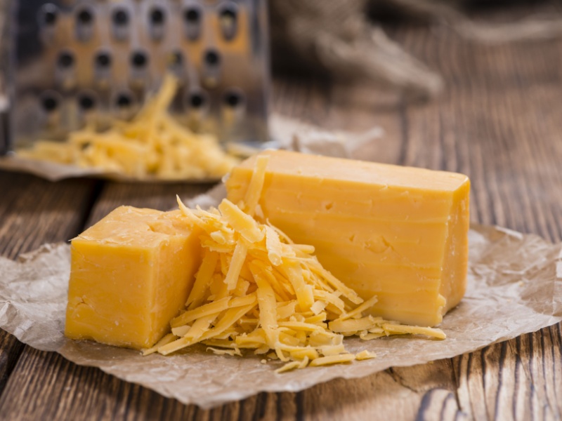 A block of half-grated cheddar cheese.