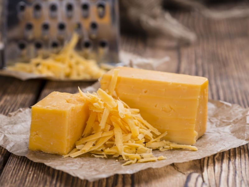 A block of half-grated cheddar cheese.