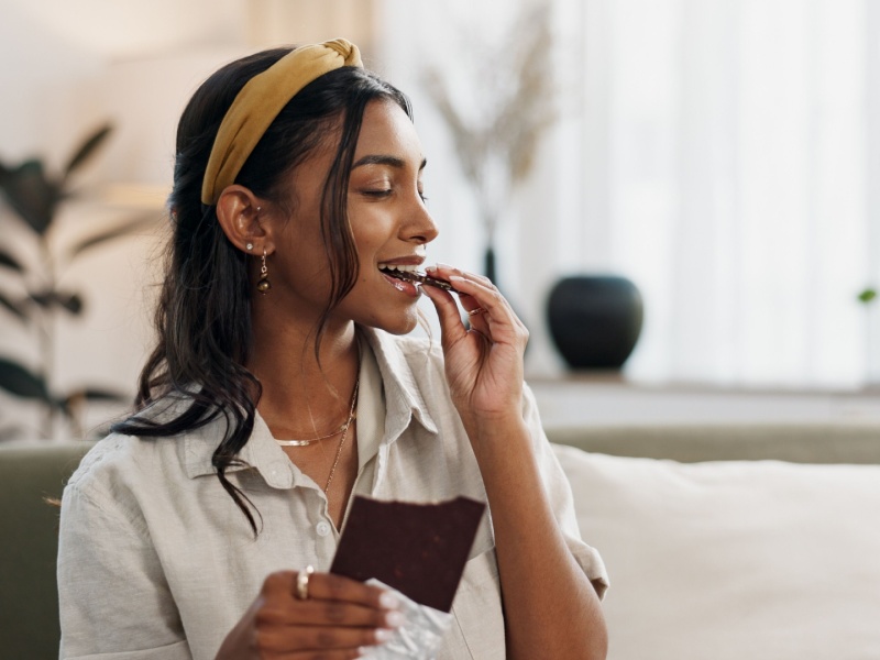 A woman eating a bar of dark chocolate.