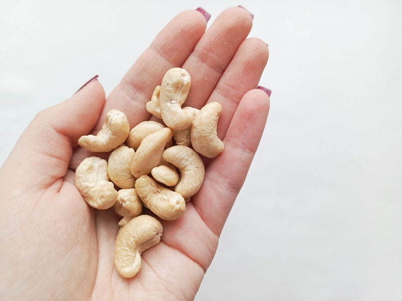 A hand holding a handful of cashews.