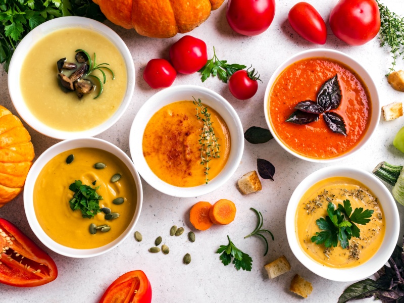 Aerial shot of 5 different soups on a table.
