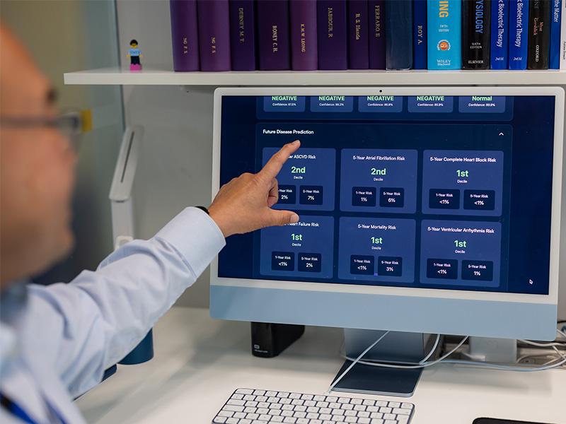 Professor Ng pointing to an AI model estimating the risk of different health conditions.