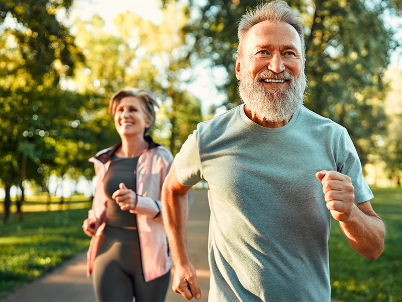 A man and woman jogging in a park.