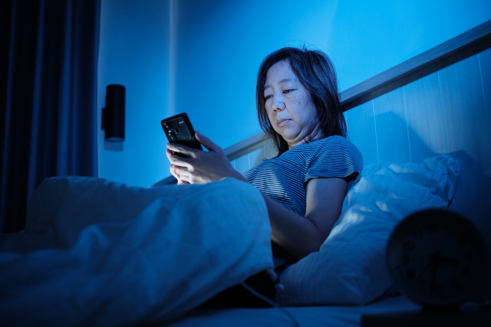Woman in bed looking at screen can't sleep 