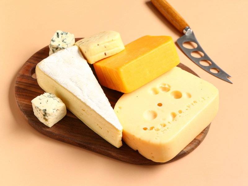 Different cheeses on a wooden board.