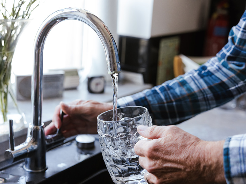 Nigel pouring a glass of water from the tap.