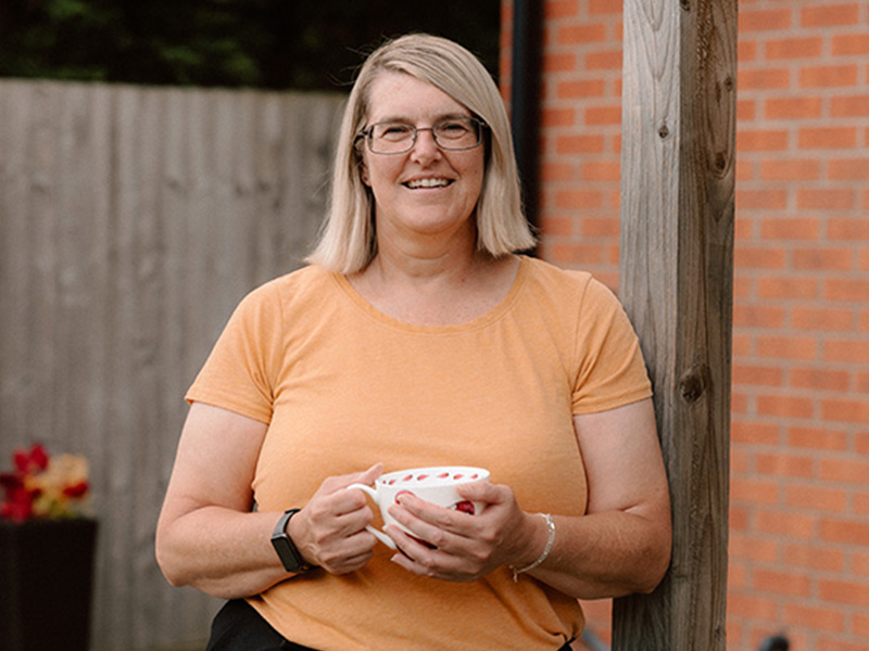 SCAD patient Allison Lawson in garden holding a cup of tea