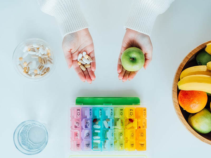 Pills and apples in hands lowering cholesterol