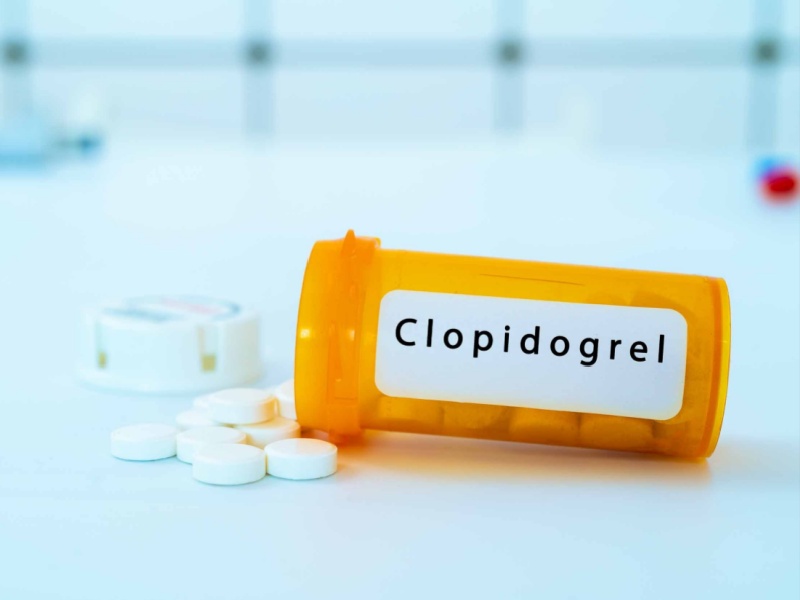 Pills spilling out of a medicine bottle labelled clopidogrel.