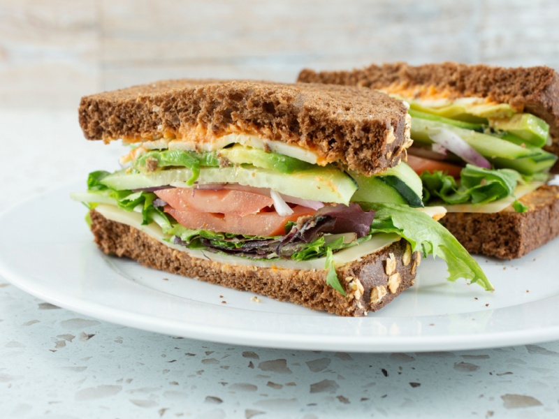 A sandwich filled with salad, cucumber and tomato.