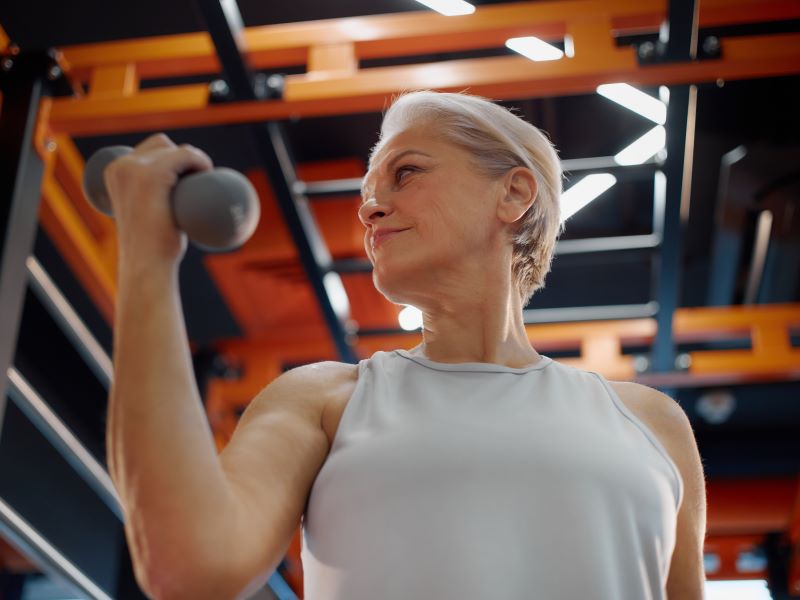 A woman in a gym lifting a weight to perform a bicep curl.