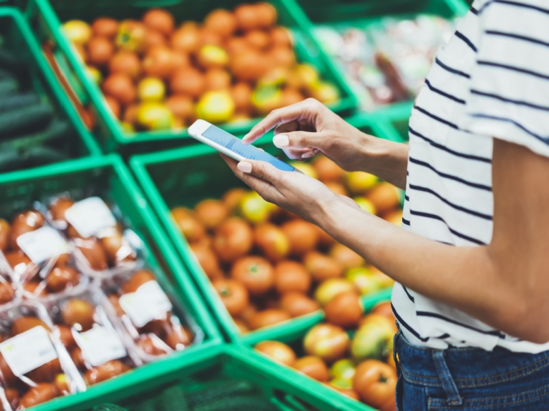 Woman in supermarket checking her shopping list on her phone.