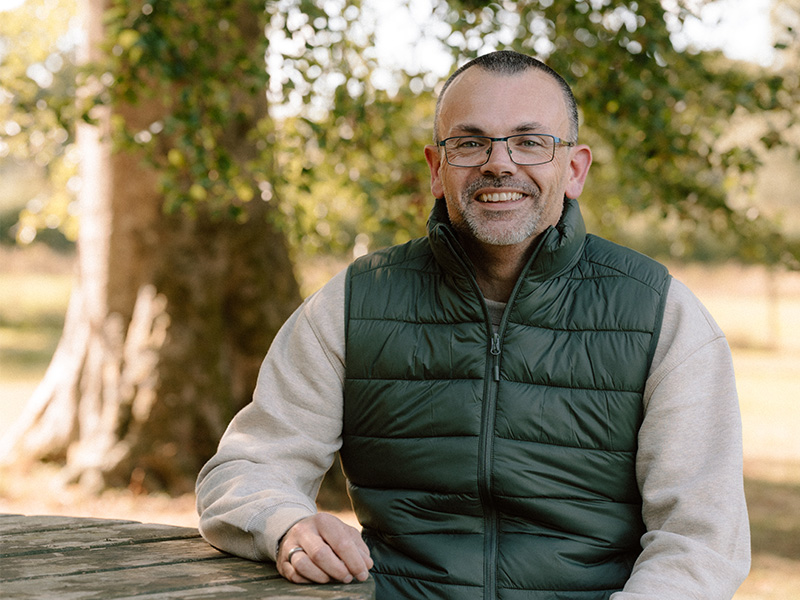 Ben Aitken sitting outside at a picnic table.