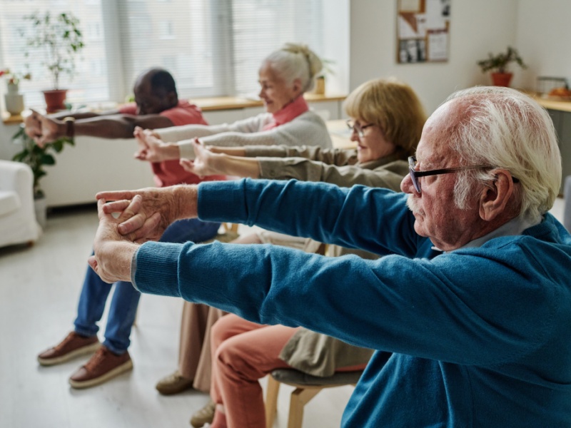 Four people in an exercise class stretching their arms.