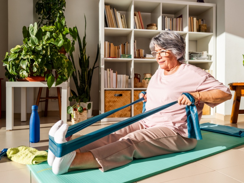 A woman exercising at home with a resistance band.