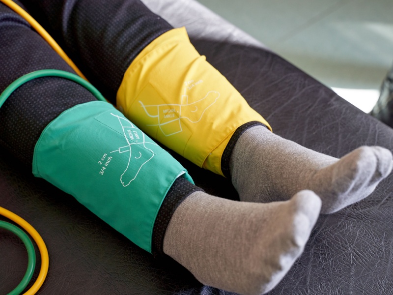 Blood pressure cuffs around someone's ankles to measure their ankle-brachial index (ABI).