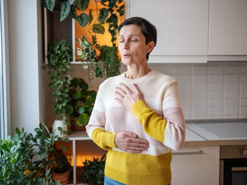A woman at home doing breathing exercises.