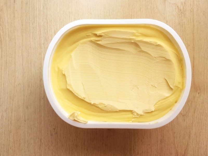 An open tub of margarine on a table.