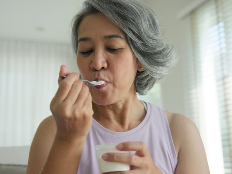 A woman eating a pot of yogurt.
