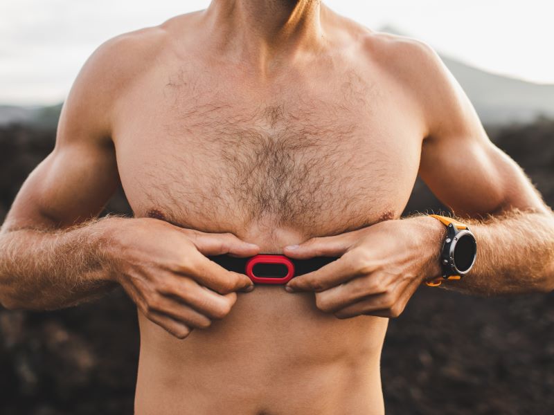 Close up of an athletic man without a top wearing a chest strap heart rate monitor