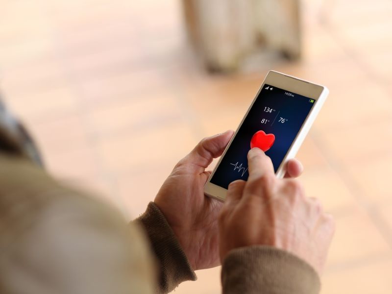 Close up of a senior person holding a phone with data about their heart rate on the phone screen