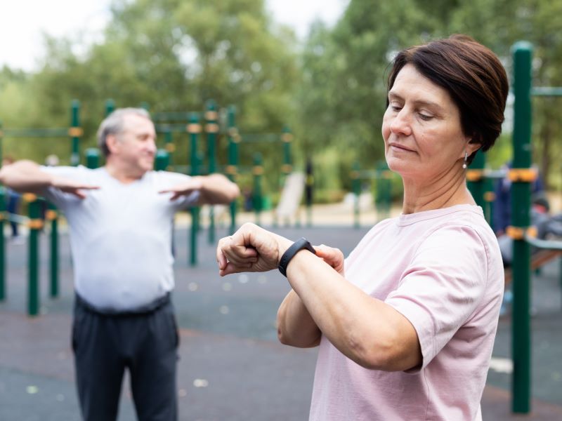 Older adults exercising together standing by fitness equipment in a park