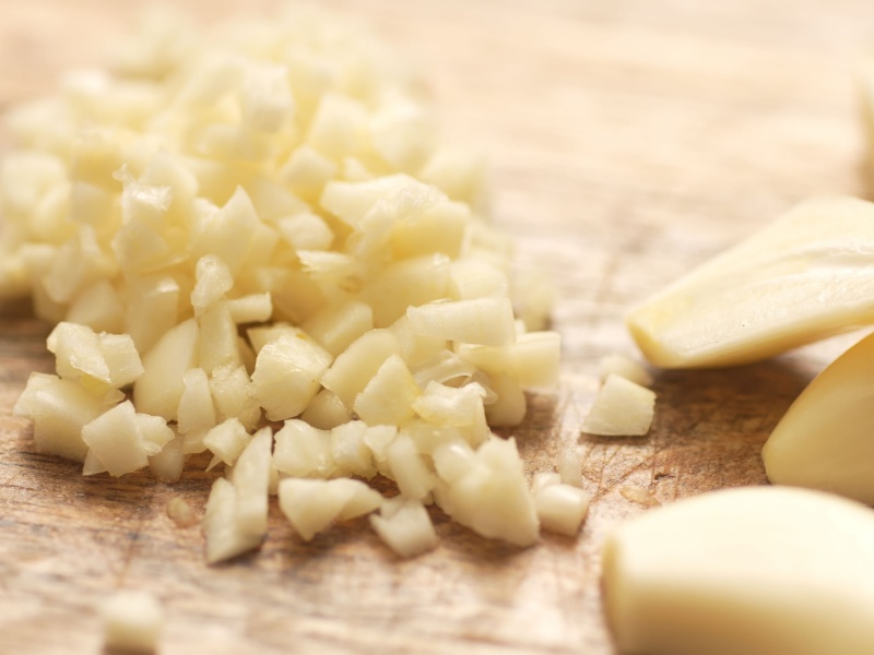 Peeled and chopped garlic cloves on a cutting board.