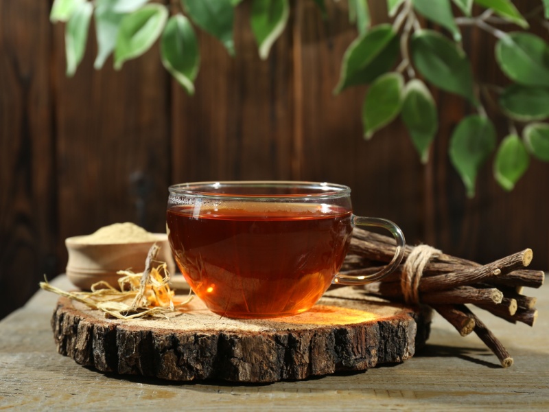 A cup of liquorice tea next to liquorice root.