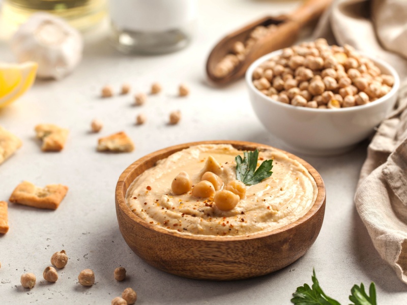 A bowl of hummus next to a bowl of chickpeas.