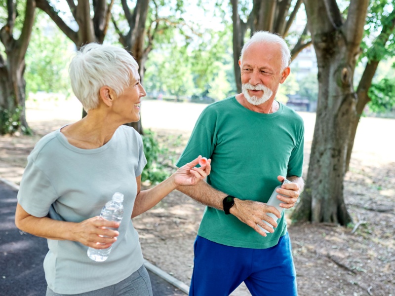 A woman and man walking outside together in a park.