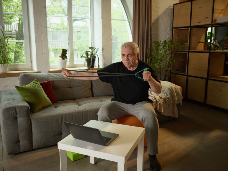 A man at home exercising with a resistance band.