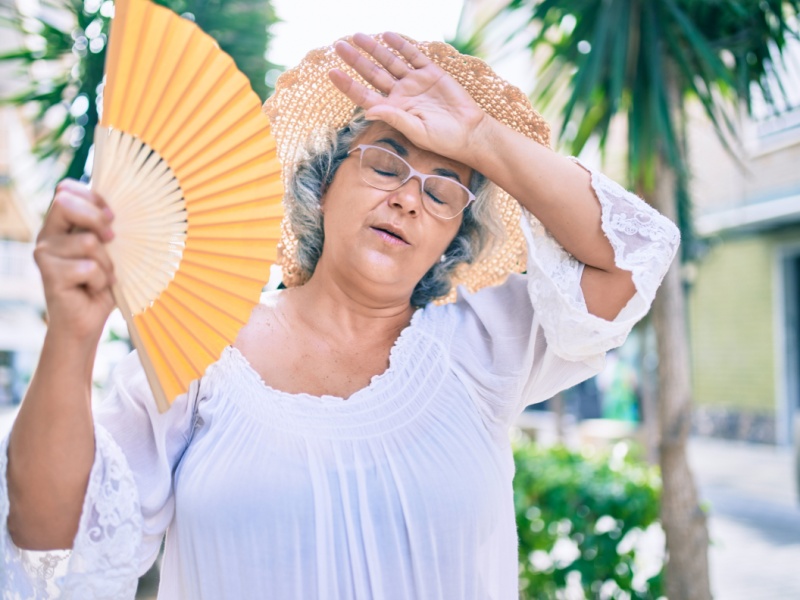A woman walking outside with a fan.